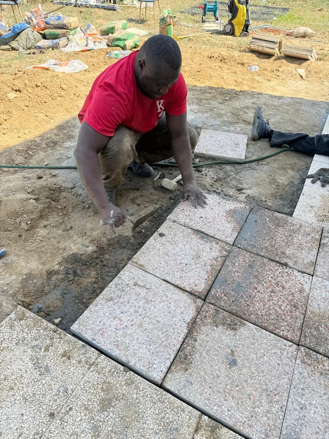 Ouvrier posant des dallettes sur lit de mortier lors d’un chantier de terrasse en Île-de-France